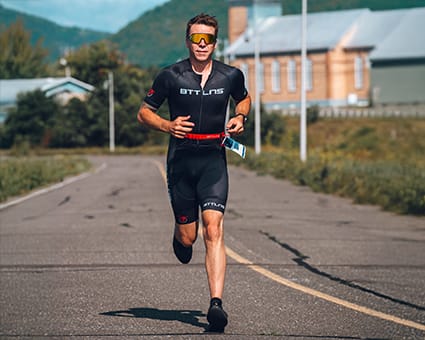 Man running in a BTTLNS trisuit on the road